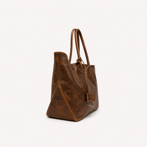 A brown distressed leather tote bag with dual shoulder straps and a small hanging metal keyring, shown from a three-quarters angle on a light off-white background.